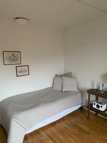 a white bedroom with a bed with a night stand at Guestroom in central Malmö in Malmö