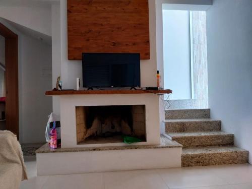sala de estar con chimenea y TV de pantalla plana en Casa da Totonha en São Lourenço do Sul