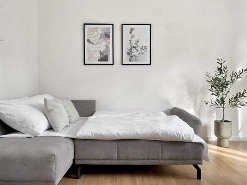uma sala de estar branca com um sofá e três fotografias na parede em *Ferienwohnung in Schwarzwald Villa für 6 Pers.* em Furtwangen