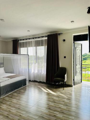 1 dormitorio con 1 cama, 1 silla y 1 ventana en Kacoke Madit Hotel and Cultural Centre, Gulu, en Gulu