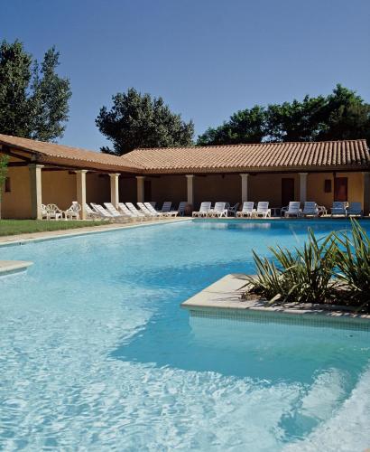 une grande piscine avec des chaises et un bâtiment dans l'établissement Villa de Trouchaud, à Aigues-Mortes