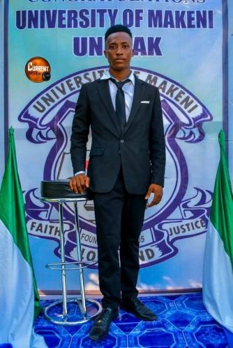 a man in a suit and tie standing next to a stool at MAKENI CITY in Kamakwie