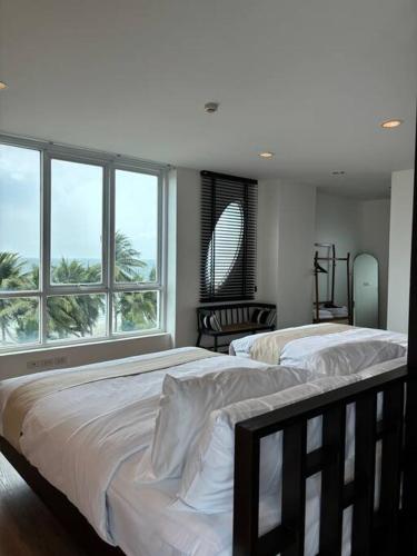 two beds in a bedroom with a large window at Beachfront 70 sqm Premier Sea View and Pool View Family Room FREE DISNEY PLUS in Ban Bang Saen (1)