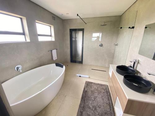 a bathroom with a large white tub and a sink at Exquisite premium Fulatha Suite - 2202 in Bulawayo