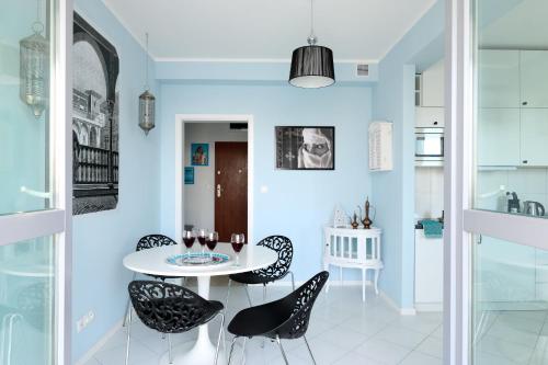 a dining room with a white table and black chairs at Sleep Dream in Warsaw