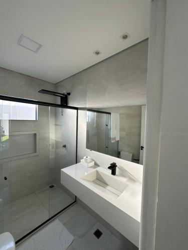 a white bathroom with a sink and a shower at Cantinho do sossego in Porto Seguro