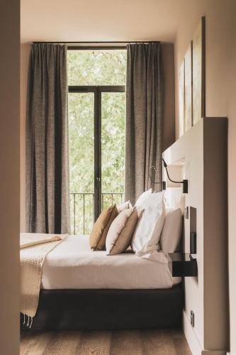 a bedroom with a bed with pillows and a window at Les Lodges Sainte-Victoire Hotel & Spa in Aix-en-Provence