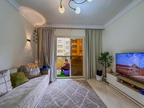 een woonkamer met een bank en een flatscreen-tv bij Joe Excellence Residence in Caïro