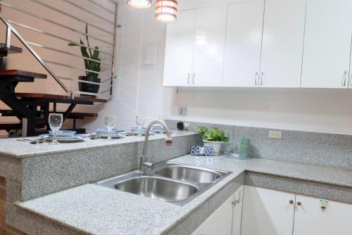 a kitchen with a stainless steel sink and white cabinets at Strata Homestay- Luxurious 2- Storey Townhouse in Baguio