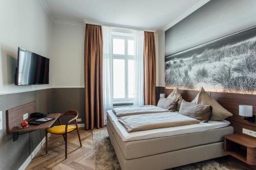 a hotel room with a bed and a desk at Strandhotel Hohenzollern in Borkum