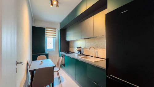 a kitchen with green cabinets and a table and a sink at Como Life Inn in Bragadiru