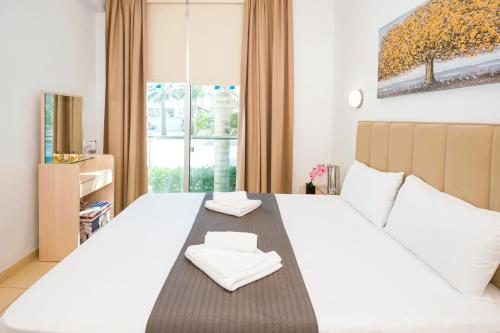 1 dormitorio con 1 cama grande y 2 toallas blancas en ALICIA - Beachfront Apartment, en Paralimni