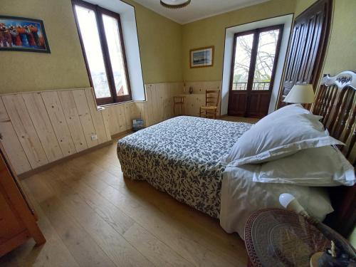 um quarto com uma cama e duas janelas em Duplex dans maison Chez Bastien em Mouxy