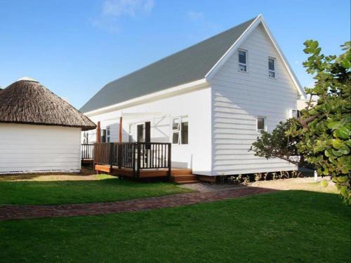 a white house with a porch and a roof at Seals Backpackers in Cape St Francis