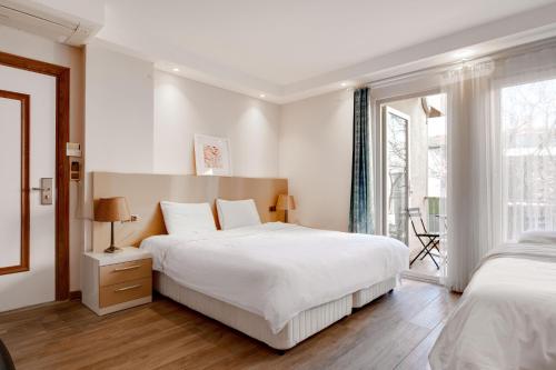 a white bedroom with two beds and a window at Yankı Otel in Çekirge