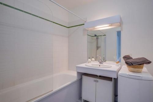 La salle de bains blanche est pourvue d'un lavabo et d'une baignoire. dans l'établissement Charmant Appartement avec Jardin, à Pessac