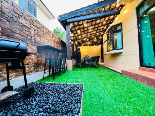 an outdoor patio with green grass and a grill at Relaxed Family Home by StayCo - Quiet Neighbourhood in Ayer Itam