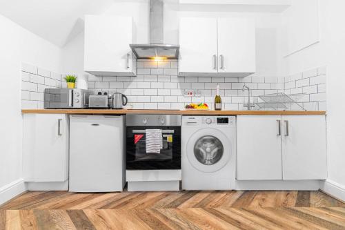 una cocina blanca con lavadora. en Wolverhampton Luxury Apartment - Free Wifi & Netflix - On Street Parking 12C en Birmingham