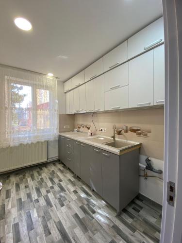 - une cuisine avec des placards blancs et un évier dans l'établissement SorinaApartament, à Tîrgu Neamţ