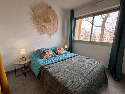 um quarto com uma cama com lençóis azuis e uma janela em Superbe T2 au calme avec balcon sur la marina - 10 em Canet-en-Roussillon