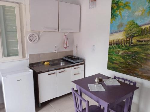 una cocina con fregadero, mesa y una pintura en Casa do Mato II en São Lourenço do Sul
