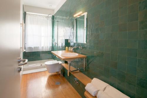 Baño de azulejos verdes con lavabo y aseo en Fil's Place, en Oporto