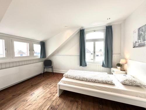a white bedroom with a bed and two windows at Business Apartments Niederbipp ZIMMERzuVERMIETEN in Niederbipp