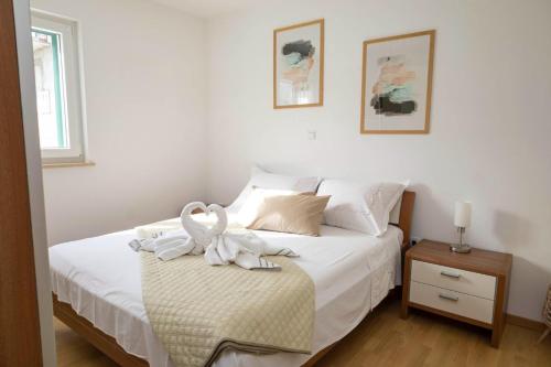 a bedroom with a bed with white sheets and towels at Bella Vita in Trilj