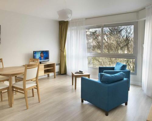 a living room with a blue couch and a dining room table at Domitys Paris Plaisance in Paris