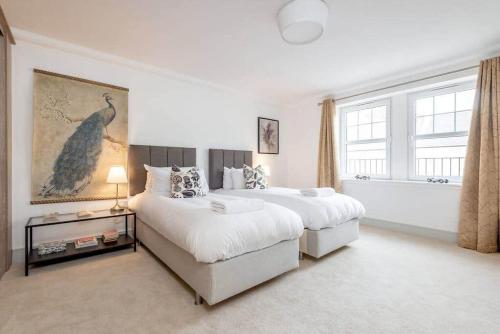 a white bedroom with two beds and a large window at Kinness House, Luxury Apartment with Parking in St Andrews
