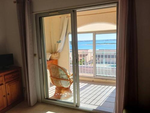 d'une porte coulissante en verre avec une chaise sur le balcon. dans l'établissement Appartement avec magnifique vue sur mer, à Gruissan
