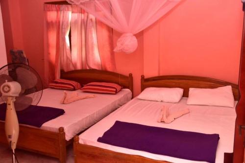 two twin beds in a room with a fan at Mountain Top Guest in Bandarawela