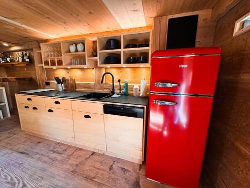a red refrigerator in a kitchen with a sink at Ferienhaus Spycher im Emmental in Lützelflüh