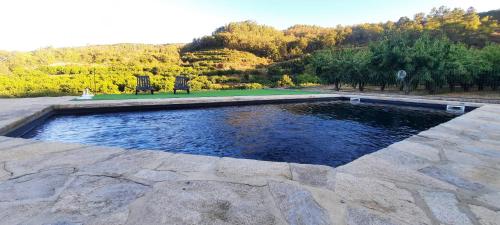 a pool of water with two chairs in a park at Quinta do Limite - Agroturismo in Covilhã