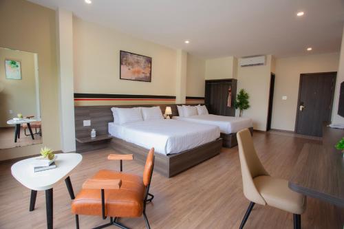 een hotelkamer met 2 bedden en een tafel en stoelen bij CENTRAL BOUTIQUE HOTEL in Da Nang