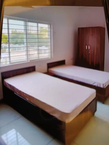 two beds in a room with a window at Vaatsaly home in Indore