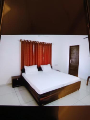 a bedroom with a white bed with a red curtain at Vaatsaly home in Indore