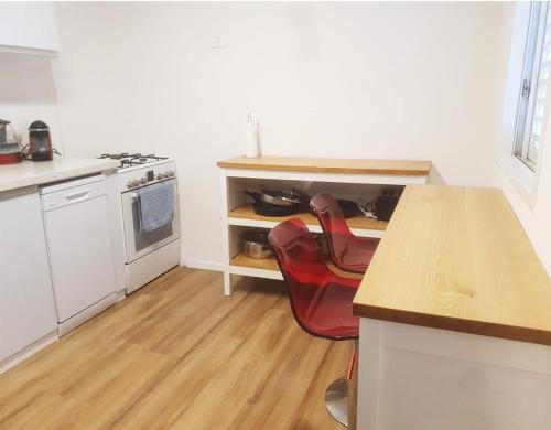 a kitchen with a counter and a red chair in it at Spacious 3BD Penthouse with Rooftop & Parking in Ra‘ananna