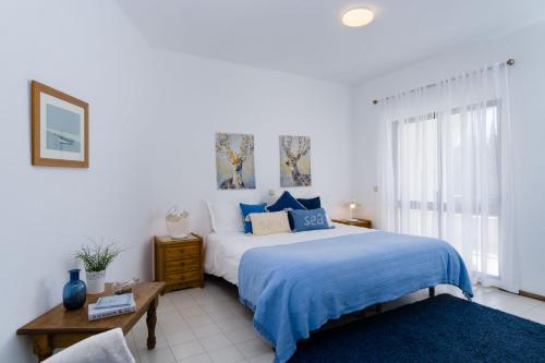 Schlafzimmer mit einem blauen und weißen Bett und einem Fenster in der Unterkunft Paradise Coastal Beach House in Porches