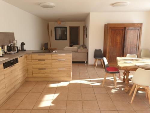 una cocina con armarios de madera, mesa y sillas en Luciole des Alpilles, en Mouriès
