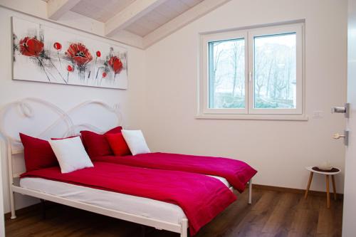 a bedroom with a bed with red sheets and a window at Ivana-suite CIPAT 022104-AT-013433 in Levico Terme