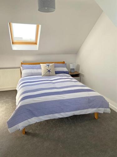 a bedroom with a blue and white striped bed at 2 Headland Place Aberporth (Beautiful sea views, 1 min walk to beach) in Aberporth