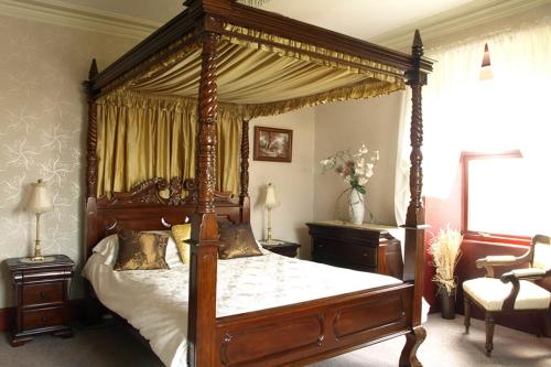 a bedroom with a canopy bed and a chair at Duddon Villa in Millom