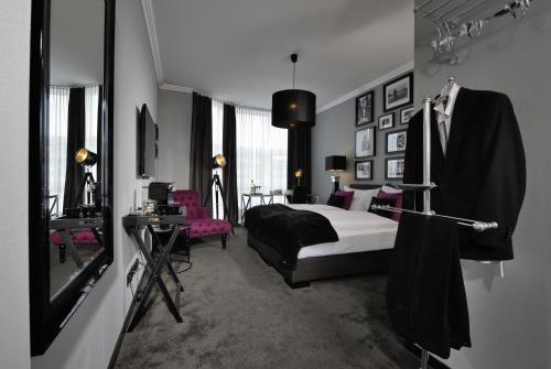 a bedroom with a bed and a table and a mirror at Hotel Friends Hückelhoven in Hückelhoven