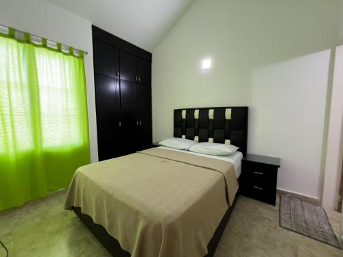 a bedroom with a large bed and a green curtain at Tucacasposadas in Tucacas