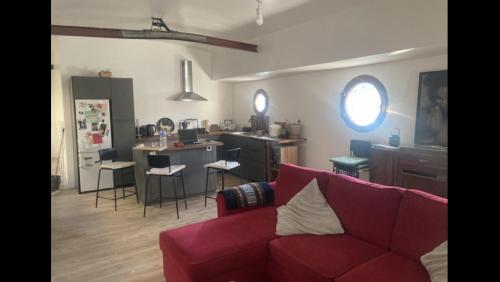un soggiorno con divano rosso e una cucina di Péniche logement d'exception sur la Seine Spécial JEUX OLYMPIQUES a LʼÎle-Saint-Denis