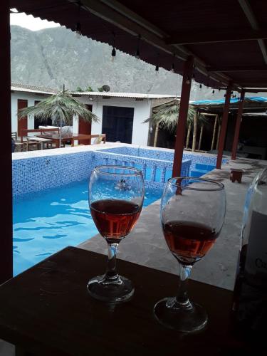 dos copas de vino sentadas en una mesa cerca de una piscina en H, en Barranca