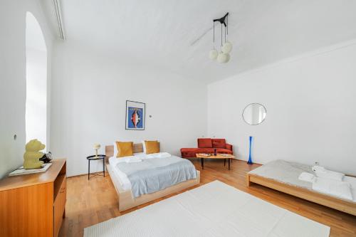 een witte kamer met een bed en een bank bij Hidden Gem with red Door in Wenen