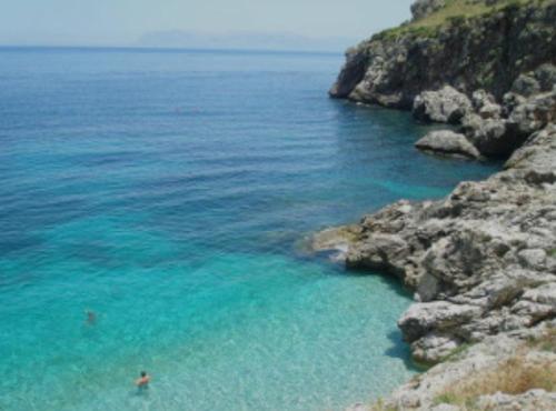 two people swimming in a body of water at Splendida Villa NATURE-APPARTAMENTO MELOGRANO a SCOPELLO-ZINGARO vista sul mare in Scopello