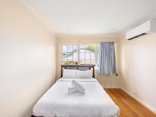 a bedroom with a white bed with a towel on it at 4BR German style Villa w Pool Eight Mile Plains in Brisbane